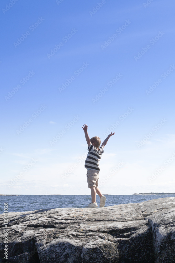 Sweden, Uppland, Runmaro, Barrskar, Boy (6-7) standing on seaside and looking at view Sweden, Uppland, Runmaro, Barrskar, Boy (6-7) standing on seaside and looking at view