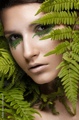 Beautiful girl with art make-up, fern leaves. The beauty of the face.
