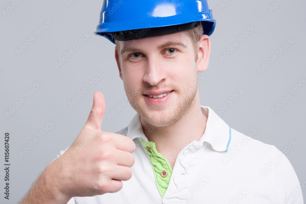 Junger Ingenieur mit Helm zeigt Daumen hoch Junger Ingenieur mit Helm zeigt Daumen hoch