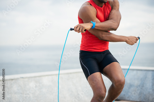 Fotografie Detail of male runner jumping rope for warming up