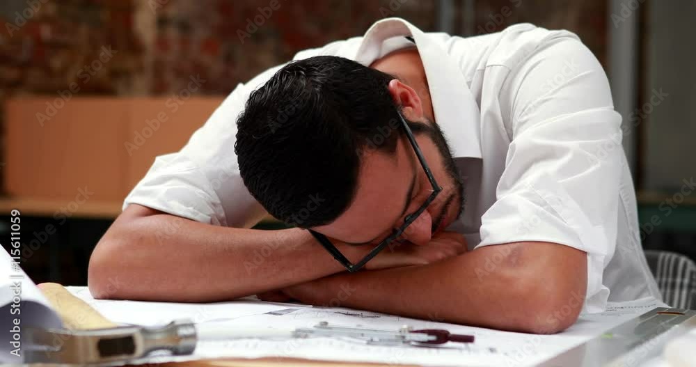 Young architect sleeping on his blueprints in the office Young architect sleeping on his blueprints in the office