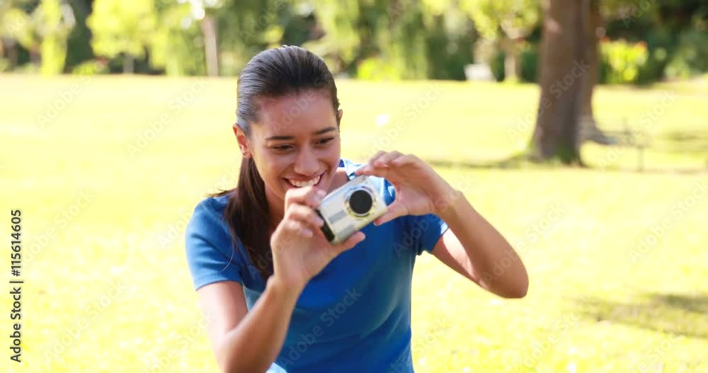 Smiling brunette taking pictures in the park on a sunny day Smiling brunette taking pictures in the park on a sunny day