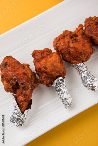 chicken lolipop, chicken winglet, tandoori chicken. Famous indian non veg dish, roasted chicken covered with silver foil, served with spicy chutney, indian chinese appetizer