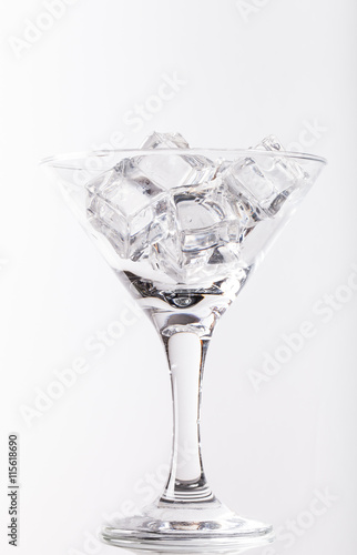 Ice cubes and martini glass on white background