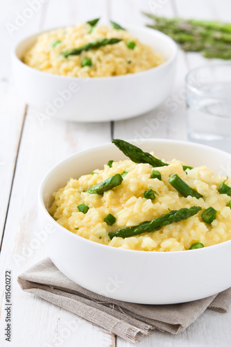 Risotto with asparagus, parsley and peas on a white wooden table