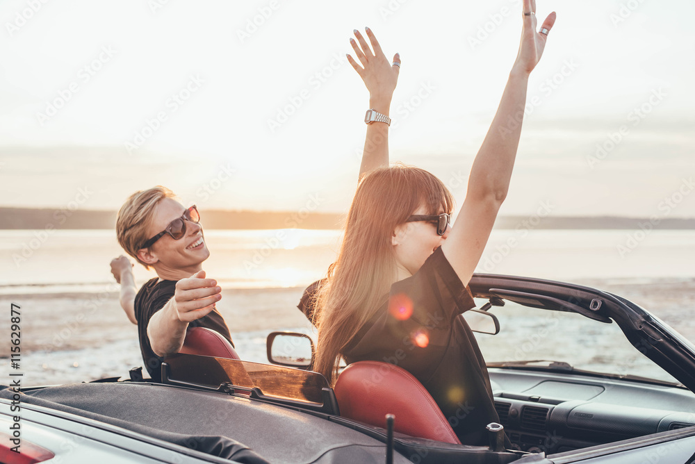 young happy couple in cabriolet in sunset light