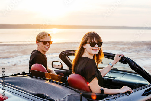 young happy couple in cabriolet in sunset light