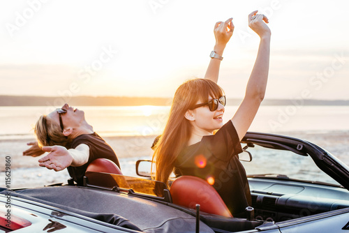 young happy couple in cabriolet in sunset light