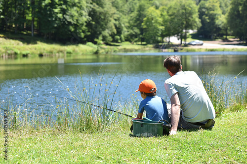 Dad with little boy fishing by mountain lake