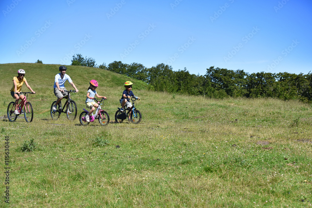 Obraz premium Parents with kids riding bikes in moutain path
