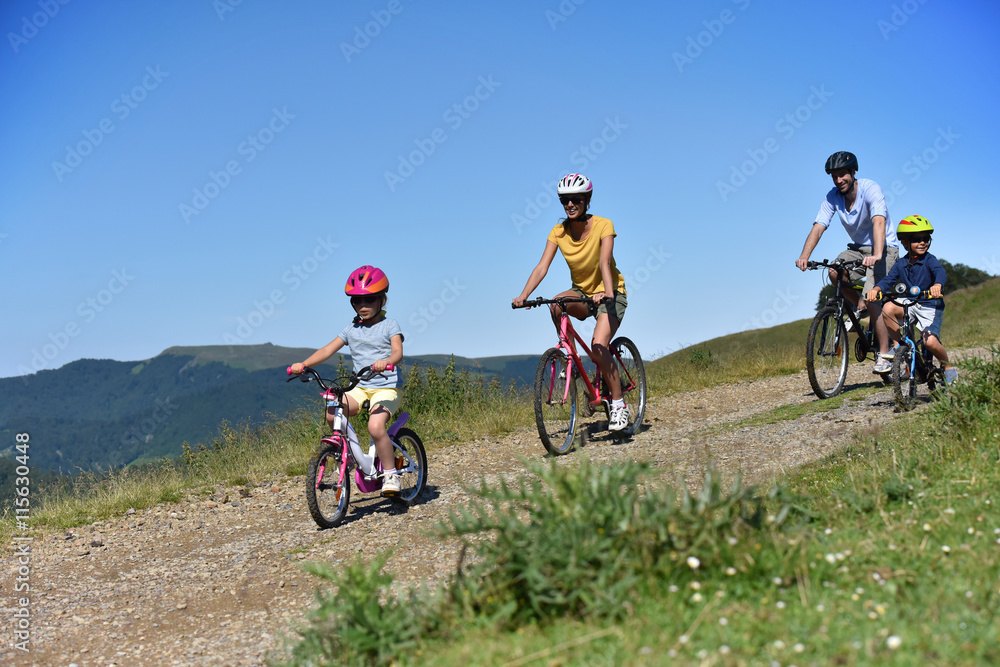 Fototapeta premium Parents with kids riding bikes in moutain path