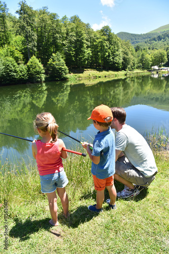 Daddy with kids fishing together by mountain lake