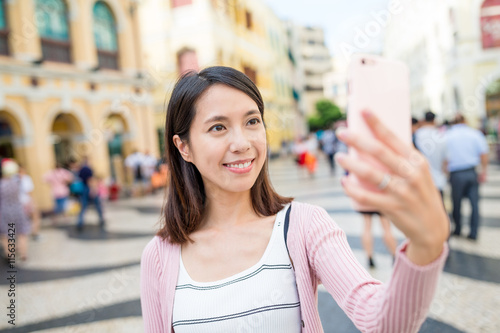 Woman taking selfie by mobile phone in Macao