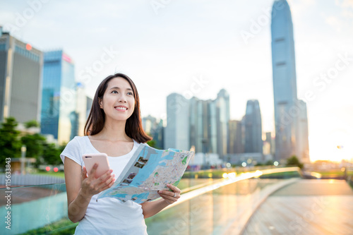 Canvas Print Woman using city map and cellphone to find the location