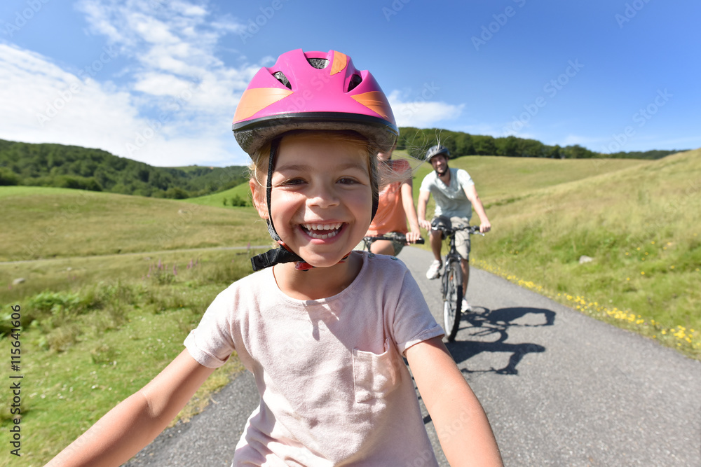 Fototapeta premium Portrait of little girl riding bike with family