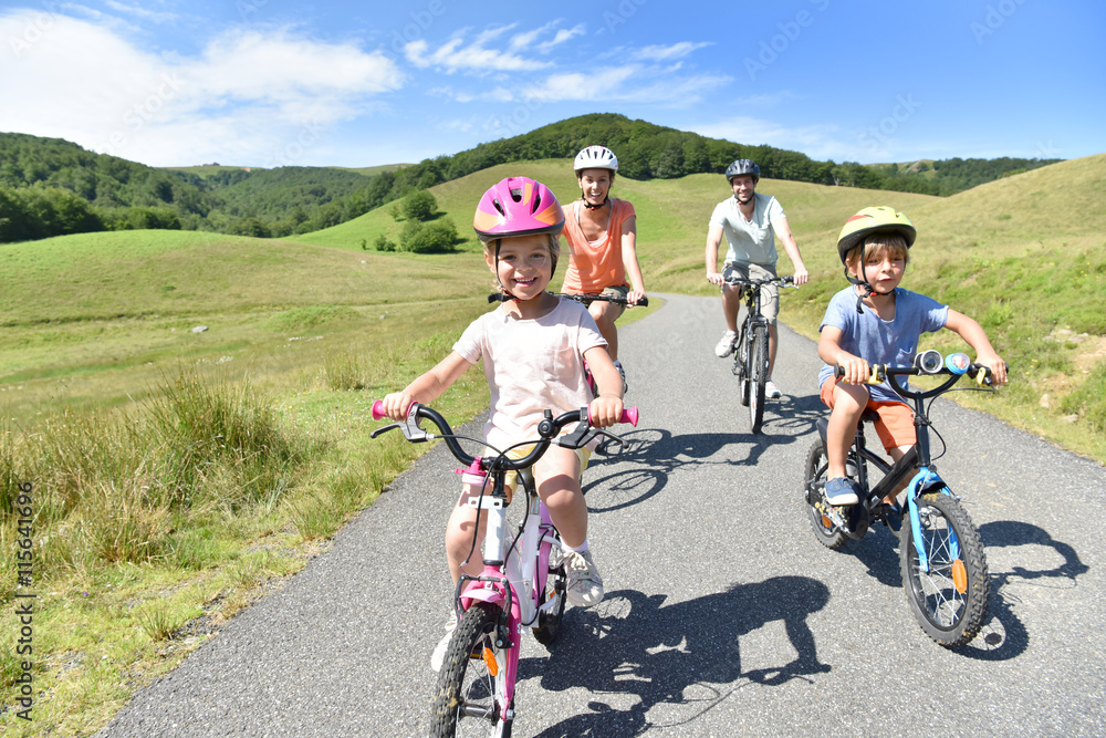Naklejka premium Happy family riding bikes in mountain road