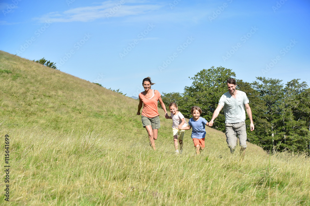 Obraz premium Family on vacation running down the hill