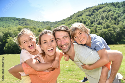 Parents giving piggyback ride to kids in mountains