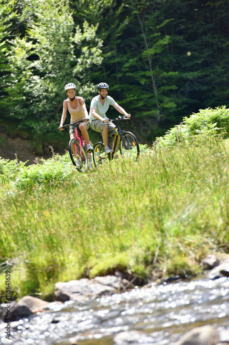 Couple riding bike in mountain field