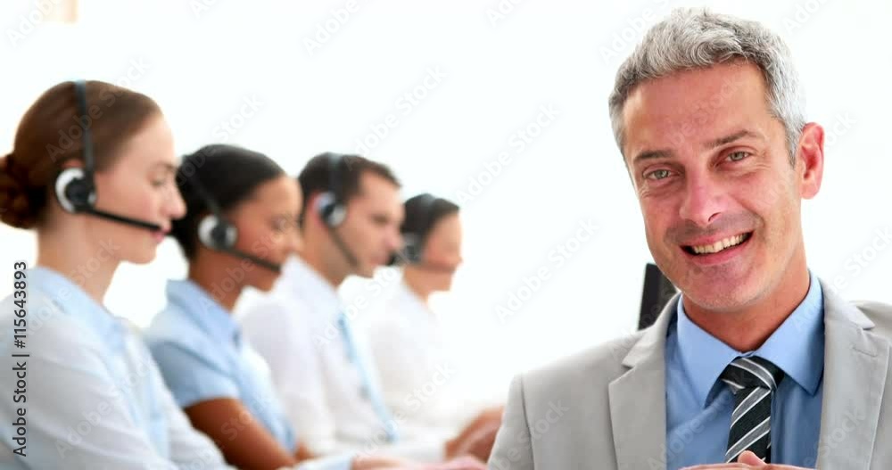 Businessman looking at camera with his colleagues behind him Businessman looking at camera with his colleagues behind him