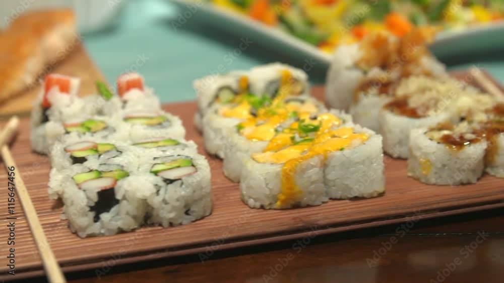 Sushi Close Up Move Right on a Table Spread. camera moves right over a variety of sushi with chop sticks, surrounded by a variety of other foods for a party
Sushi Close Up Move Right on a Table Spread. camera moves right over a variety of sushi with chop sticks, surrounded by a variety of other foods for a party