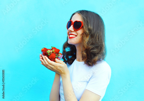 Happy smiling woman with many strawberry over blue background pr