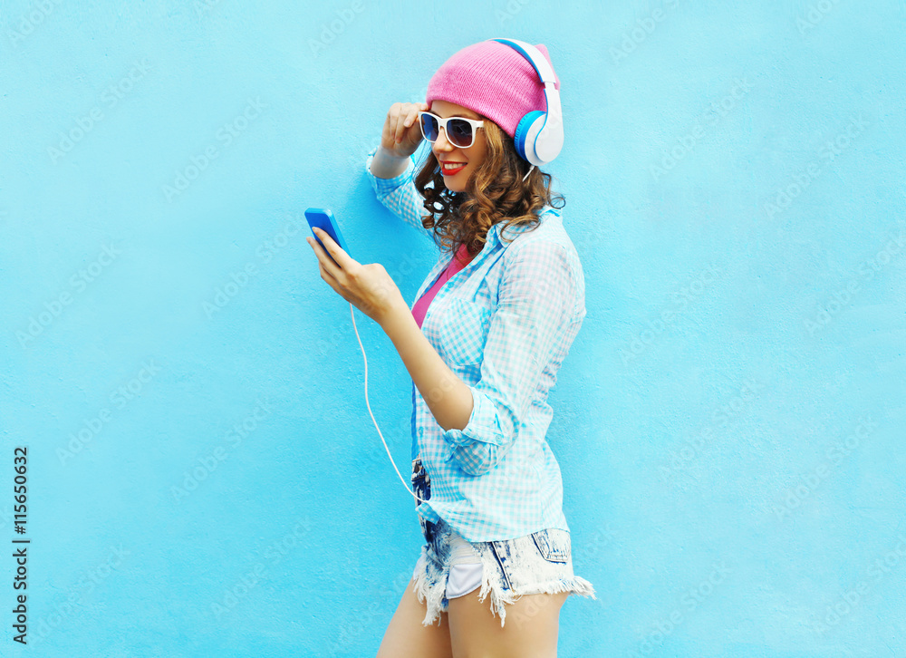 Pretty woman listens to music in headphones using smartphone ove