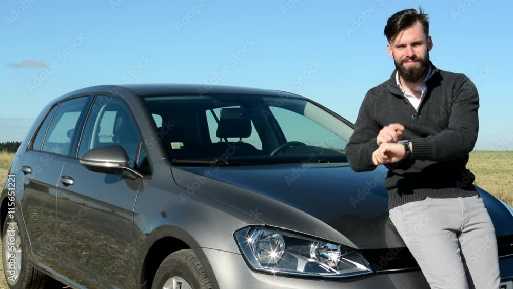 young handsome punctual strict man warn the time is already - he points the watches - eye contact - he stands by his car in the countryside young handsome punctual strict man warn the time is already - he points the watches - eye contact - he stands by his car in the countryside