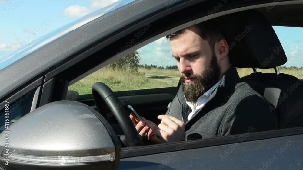 young handsome hipster man sits in the car and works on the phone - countryside - sunny weather young handsome hipster man sits in the car and works on the phone - countryside - sunny weather