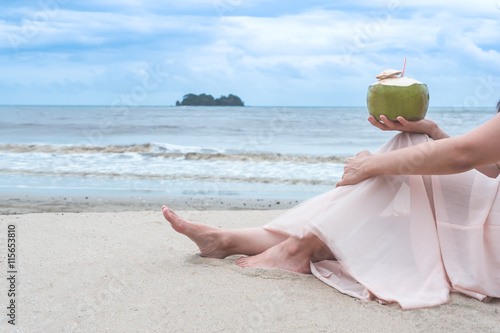 Woman`s hands holding coconut on tropical beach photo