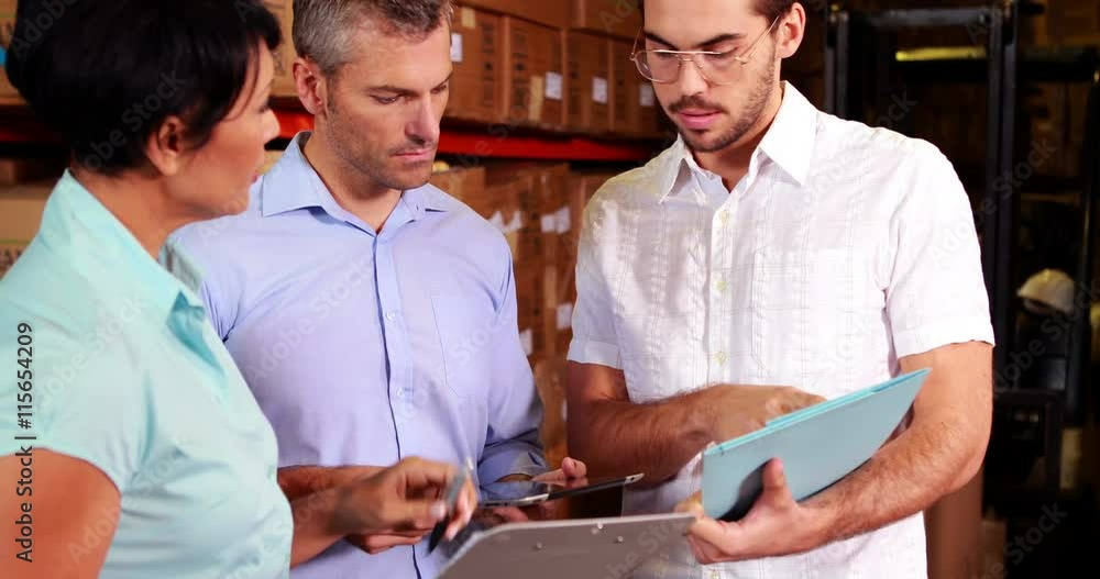 Warehouse operatives discussing file on tablet pc Warehouse operatives discussing file on tablet pc