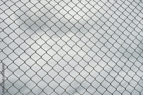 Rusty steel wire mesh fence , cloud in background