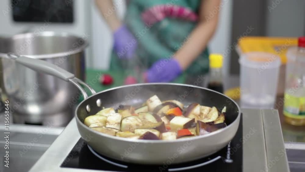 Eggplant ragout is being prepared in the pan on an electrick stove, fastfood kitchen background Eggplant ragout is being prepared in the pan on an electrick stove, fastfood kitchen background