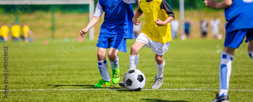 Kids playing football soccer game on sports field. Boys kicking soccer ball. Horizontal sport background