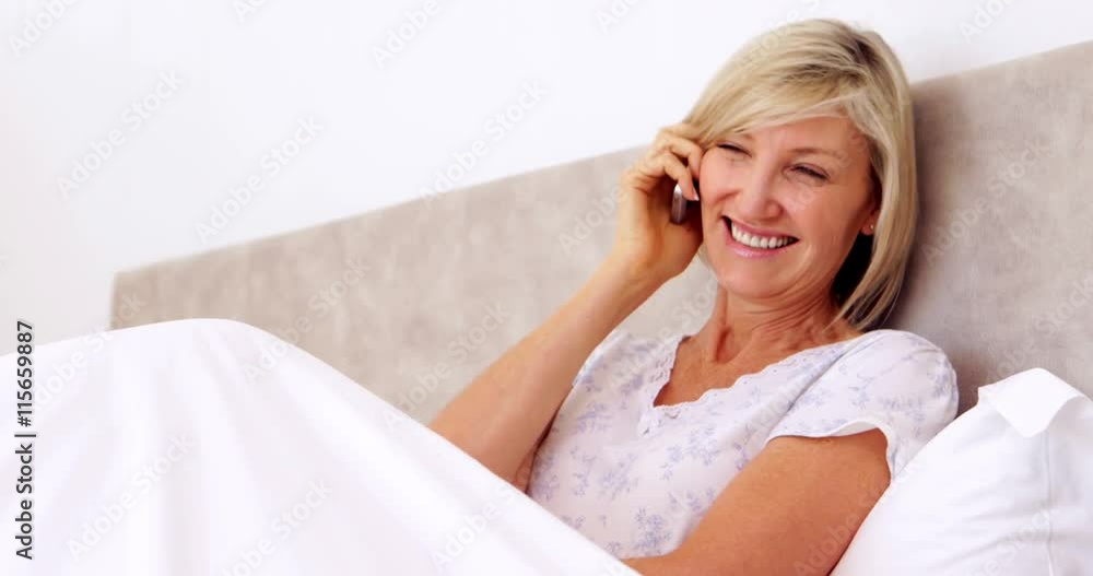 Happy woman talking on phone in bed Happy woman talking on phone in bed