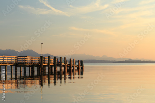 Pier at Chieming Lake Chiemsee at sunset with alpes