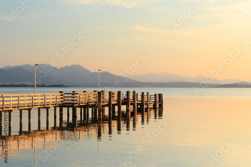 Pier at Chieming Lake Chiemsee at sunset with alpes photo