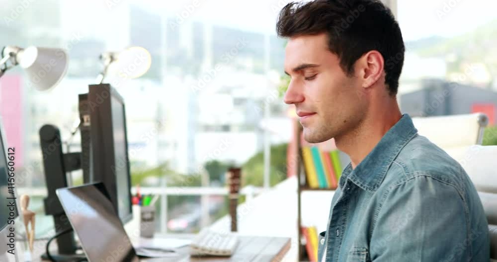 Casual businessman using computer and looking at camera Casual businessman using computer and looking at camera