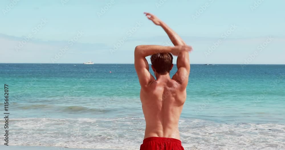 attractive man stretching his arms at the beach attractive man stretching his arms at the beach