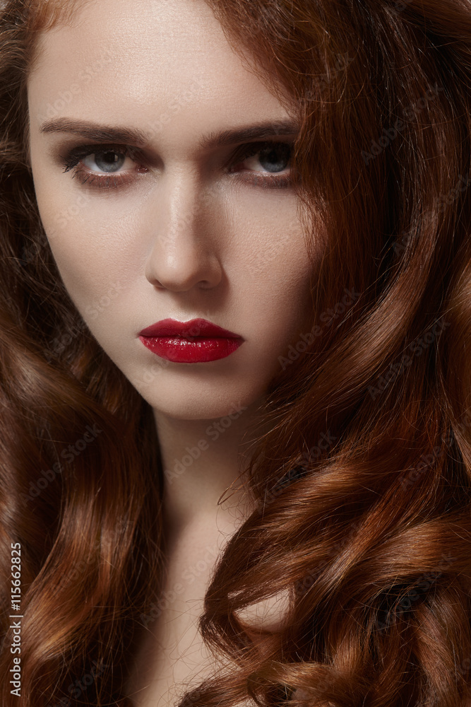 Fototapeta premium Beautiful young woman with clean skin, shiny red hair, fashion makeup. Glamour make-up, perfect blood lips. Portrait sexy ginger woman with curly hairstyle