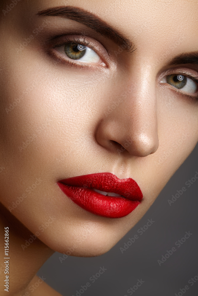 Fototapeta premium Beautiful model with fashion make-up. Close-up portrait sexy woman with glamour lip gloss makeup and black eyeliner make-up. Shot of celebrate visage, clean skin, lips with red lipstick, eyebrows