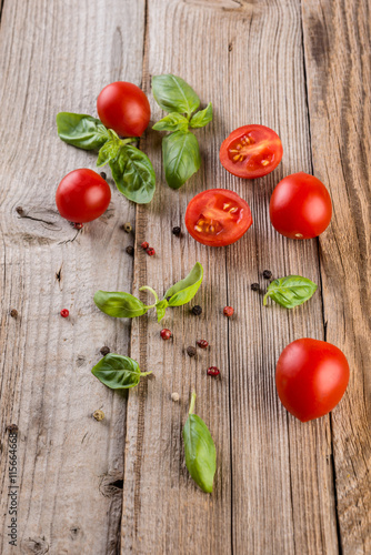 Cherry tomatoes, basil and pepper on wooden table, selective focus