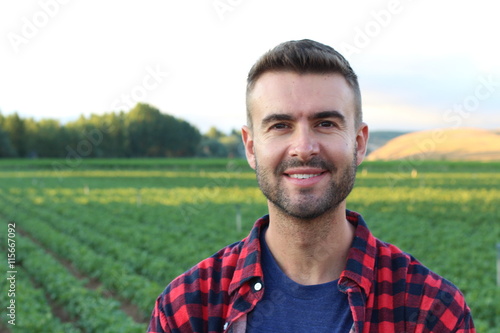 Happy smiling caucasian thirty years old farmer standing proud in front of his fields
