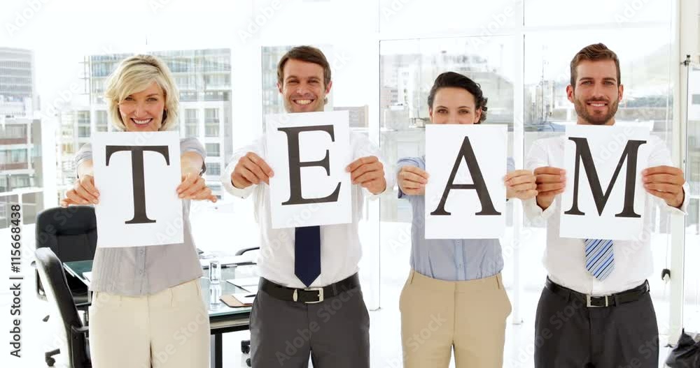 Business people holding up pages spelling out team Business people holding up pages spelling out team