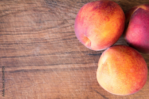 Fresh peaches on a wooden cutting board.