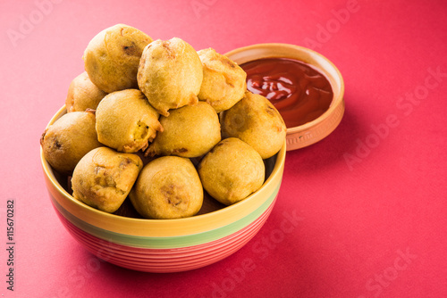 black gram or urad dal vada or pakoda or aalu bonda, aalu bonde with coconut and pudina chutney, isolated on red background, top view photo