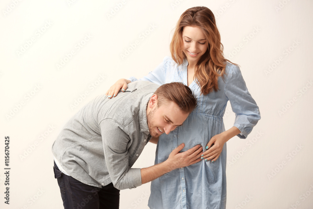 Happy family expecting baby on light background Happy family expecting baby on light background