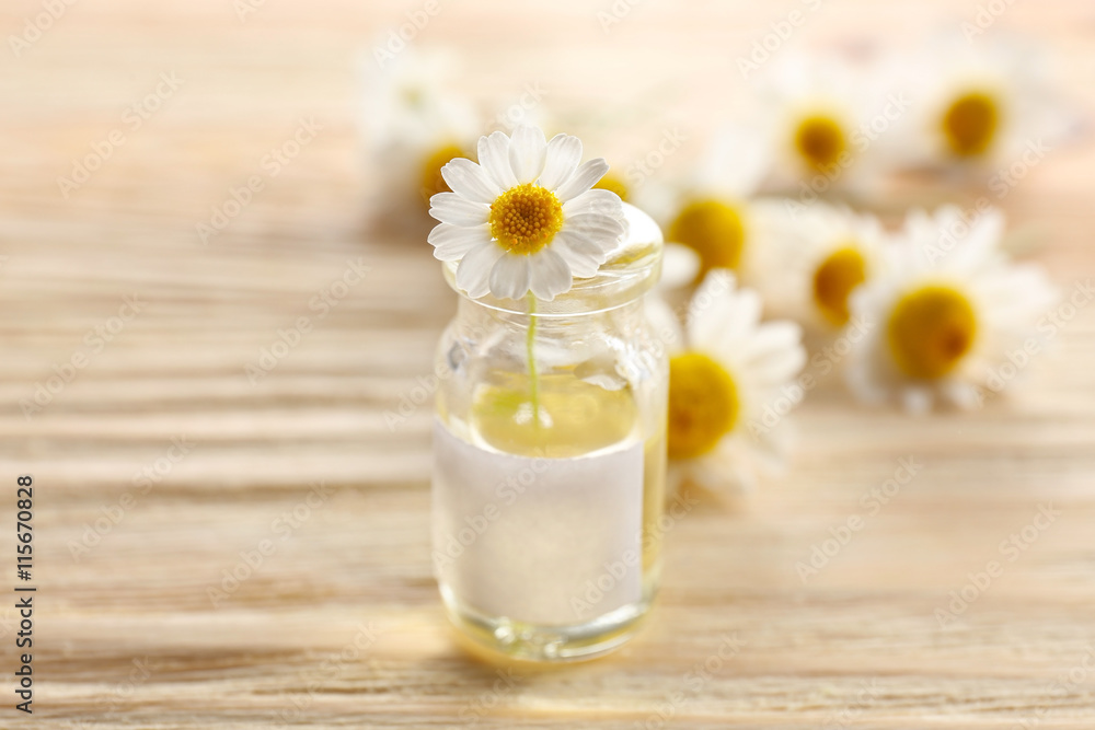 Healing chamomile flower in small glass bottle on light wooden background Healing chamomile flower in small glass bottle on light wooden background