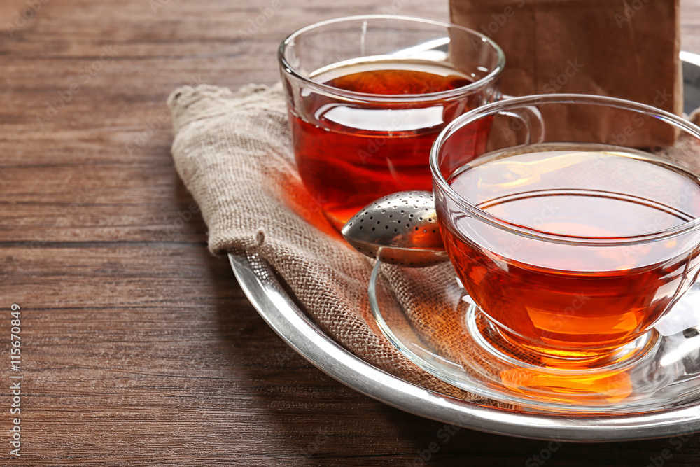 Glass cups of tea in silver tray on wooden table Glass cups of tea in silver tray on wooden table