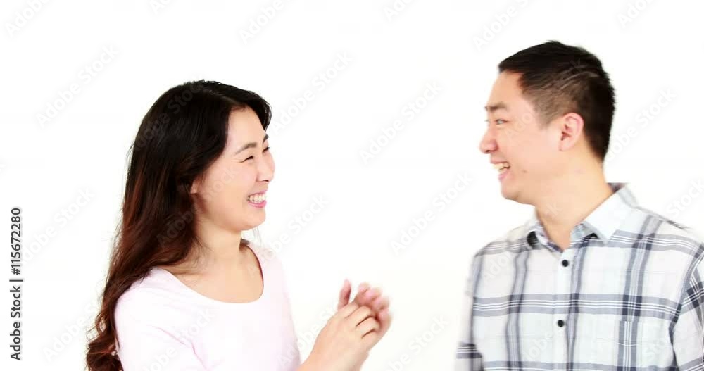 Happy couple telling secrets to each other on white screen Happy couple telling secrets to each other on white screen